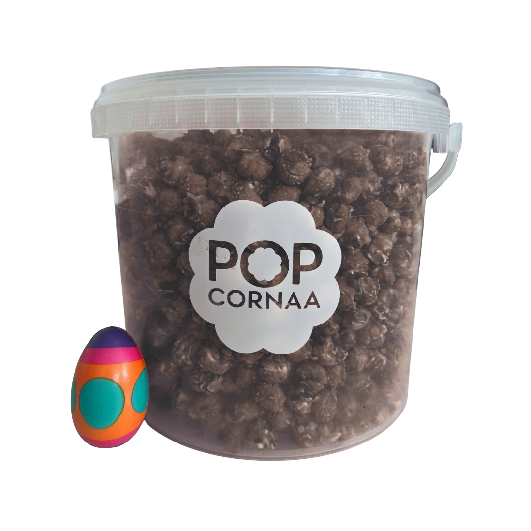 Bucket of 100% clean, dairy free chocolate orange popcorn with 'POPCORNAA' label and a colorful egg-shaped object on a white background