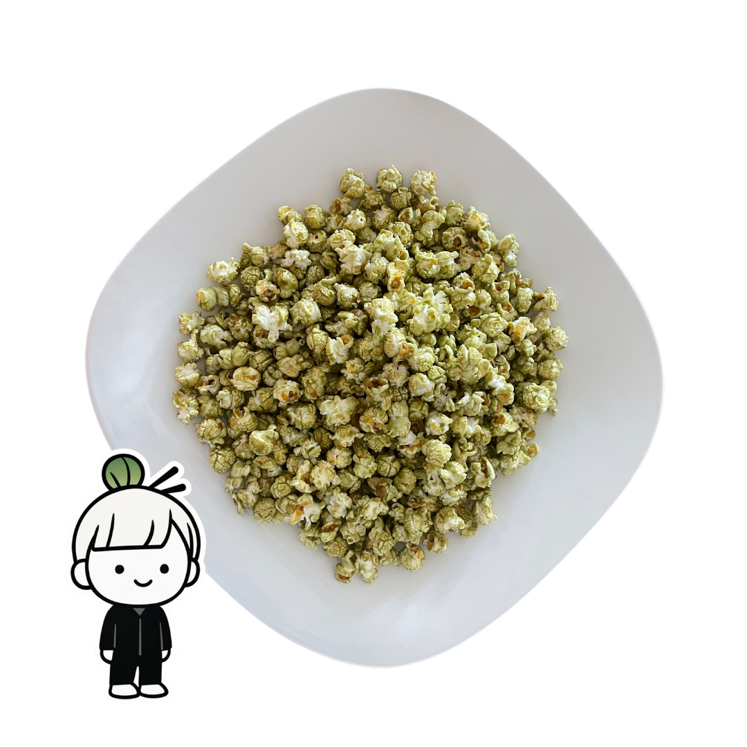 PopCornaa Green Matcha popcorn on a white plate with a small cartoon character in the corner.