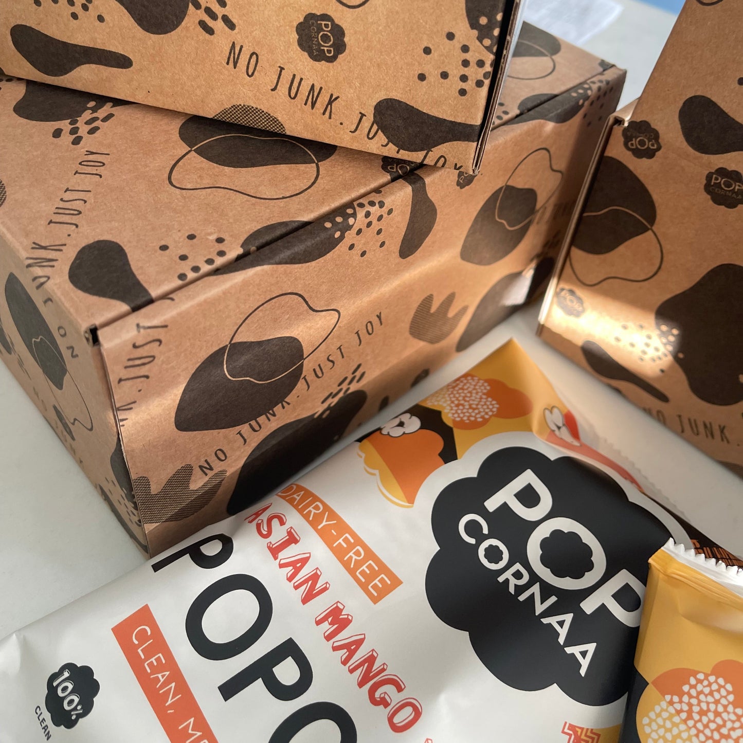 Pop Corna packaging with brown patterned boxes and a white box with branding.