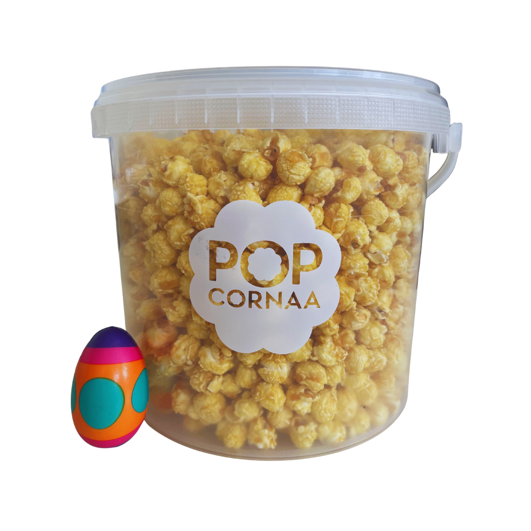 Bucket of 100% clean, dairy free Asian Mango and Limbibi popcorn with 'POPCORNAA' label and a colorful egg-shaped object on a white background