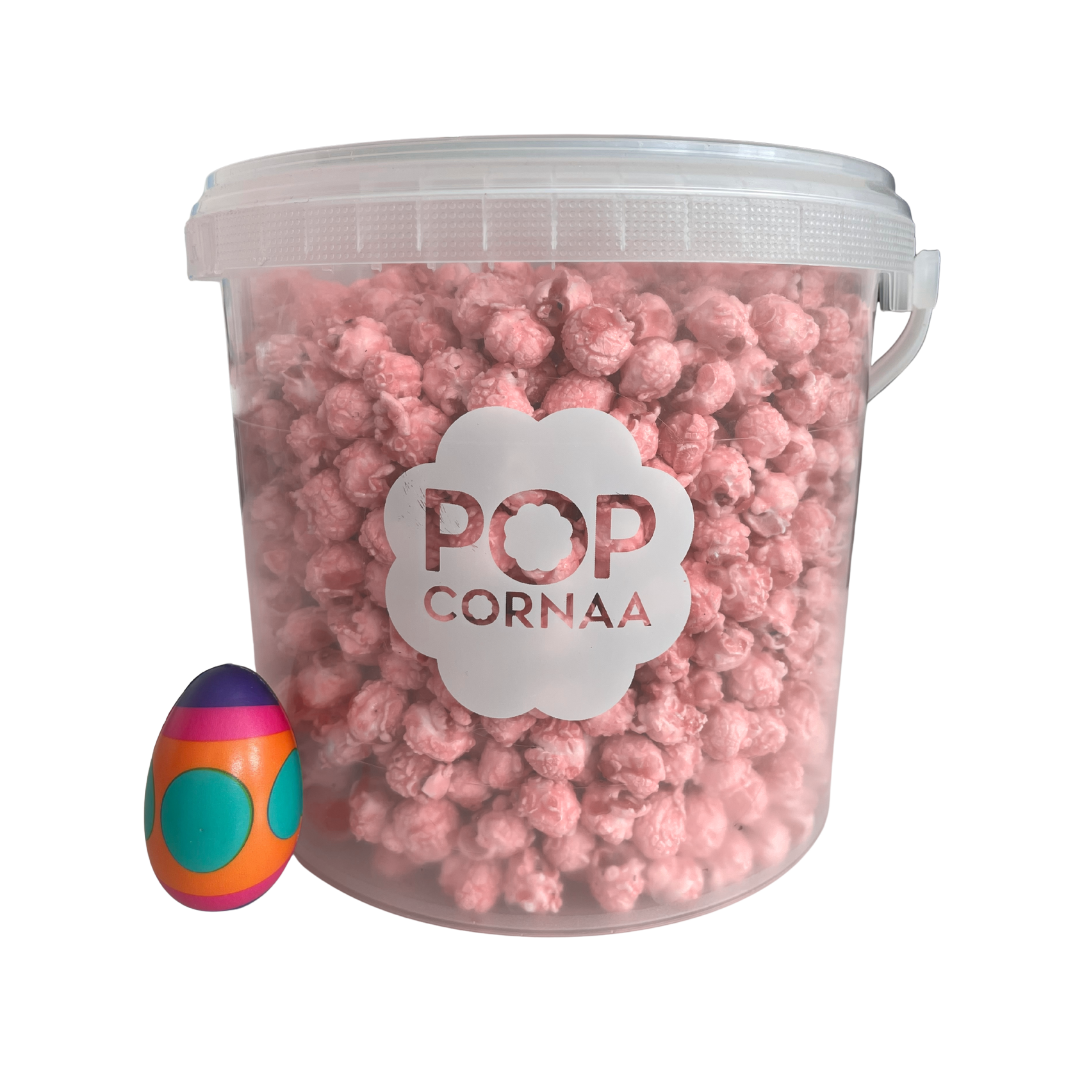 Bucket of pink litchi strawbibi  popcorn with 'POPCORNAA' label and a colorful egg-shaped object on a white background
